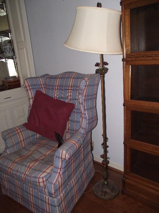 Wing back chair with plaid fabric.  Cast iron standing lamp with flower details