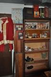Vintage Santa suit to your left, a couple of barristers/lawyers cases on their sides, and 5 stacks of cases to the right.  This photo is a couple of weeks old (it's really full now) but there are some bisque bath salt figures as well as a great collection of advertising pieces.