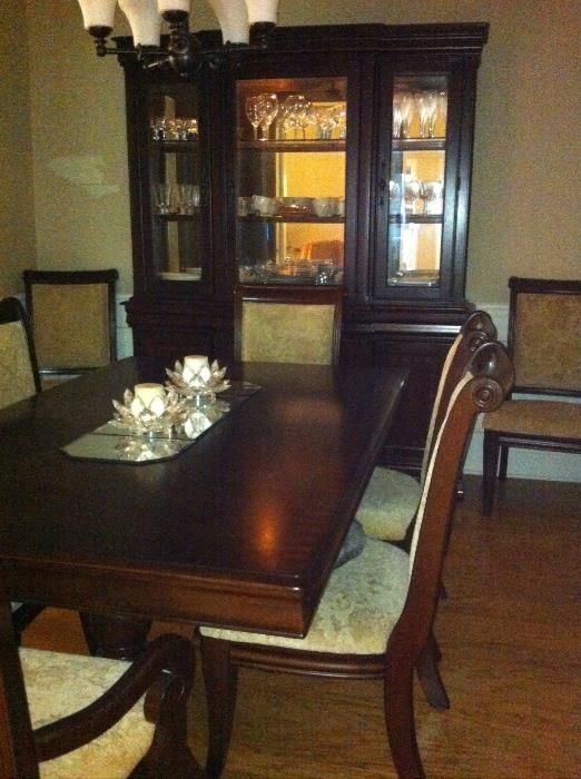 Beautiful dining room group features long formal table with 8 upholstered chairs and lighted china cabinet.