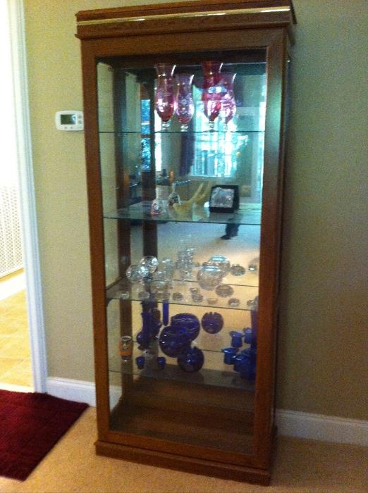 Lighted curio cabinet with mirrored back, glass shelves and side doors.