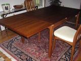 Teak expandable dining table with eight teak and fabric chairs. Rug and other items in photo are not for sale.