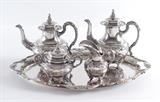 Lot 1002:  HANAU GERMAN STERLING SILVER TEA SERVICE: 5 pieces total to include 4 piece tea sterling service with embossed foliate and floral decoration, hallmark appears to be from Georg Ruttinger, marked Handarbiet (Handmade) and Sterling. 1) Coffee pot with hinged lid, 9 5/8'' h. x 9''. 2) Teapot with hinged lid, 8 3/4'' h. x 10''. 3) Covered sugar 5 3/4'' h. x 7 1/4''. 4) Open creamer, 5 5/8'' h. x 5 1/2''. Sold with 5) 800 silver tray also by Ruttinger, similar embossed design, 22'' x 16 1/2''. Approx. 81.6 troy oz. sterling, 55 troy oz. 800 silver. Estate of Col. Jack Harrison Montague, Tampa, Fl.
CONDITION: Previous owners name scratched inside lids, minor signs of use , the occasional small ding or scratch to be expected. Tray with light scratches all over.