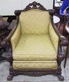 ORNATELY CARVED ANTIQUE ARMCHAIR W/TAN UPHOLSTERY.