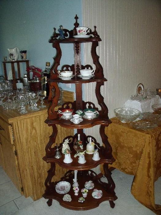 Victorian black walnut whatnot.  English bone china teacups, bells and other items on the shelves.
