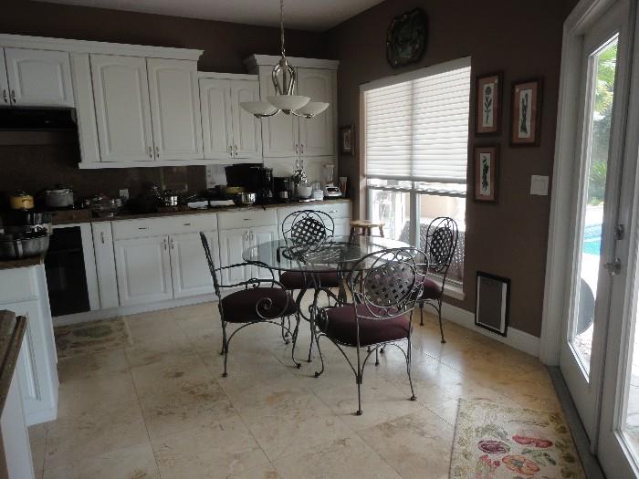 Glass top kitchen table with four chairs - maroon fabric.  Dark metal.