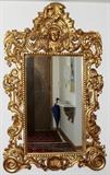 Lot#2329, GILT WOOD FRAMED MIRROR, H 46", L 26"The gilt wood framed mirror features overall scroll and foliate designs with a cherub figure in the crest.  Overall size H 76", L 51".