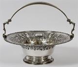 Lot#1006, GEORGE IV IRISH STERLING BASKET, DUBLIN, 1822, H 11" (TO THE HANDLE), DIA 13"A round sterling silver basket with swing handle, repousse decoration about the side includes winged nude females and eagles eating from a grape vine, the swing handle has mask and scroll terminals.  Hallmarks are partially rubbed and include the king's profile, crowned harp, Hibernia, and date letter B in an oval, along with maker's mark "SB" enclosed, possibly for Stephen Bergin (see additional photo).  Weighs approximately 43.1 troy oz.