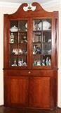Lot#1034, AMERICAN CHERRY CORNER CUPBOARD, MID 19TH C., H 83", W 48", D 22"Scroll pediment above a pair of fenestrated glazed doors opening to three fixed shelves, a drawer at the center and a pair of doors below.