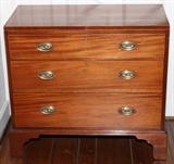Lot#1185, ENGLISH SHERATON STYLE MAHOGANY THREE-DRAWER CHEST, C. 1870, H 30"Fitted with three graduated drawers, raised on tall bracket feet, and mounted with oval brass pulls. Measuring H. 30 1/2" x 33". Circa 1870.