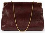 Lot#1486, JUDITH LEIBER LIZARD SHOULDER BAG, W 10"A burgundy lizard bag with gold tone accents, opening to coordinating satin lining.  Labeled:  Judith Leiber.  Measures W.10" x 7" (26" to the shoulder strap).  With felt dust bag.