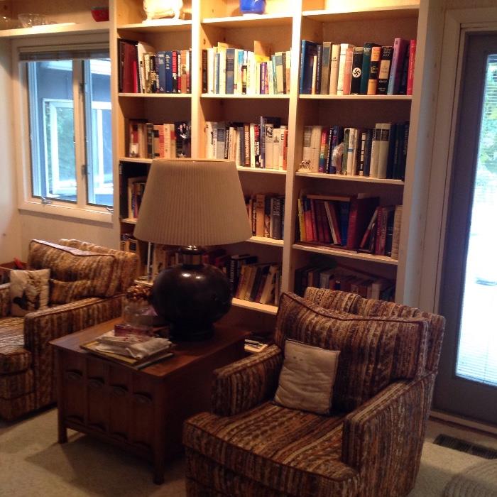 nice pair of swivel chairs around an oak side table with lamp and more books