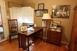 In the study, a compact desk with single drawer and slat details, coordinating chair and storage chest. Vintage photographic images and framed collections decorate the walls. BEFORE THE STORM, a photographic image by Rick Preston.