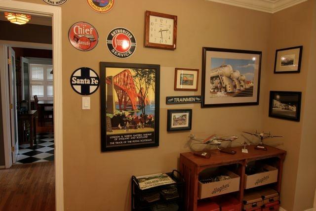 Travel themed decor lines the walls of the study. Railway posters, enameled signs and model airplanes are on display.