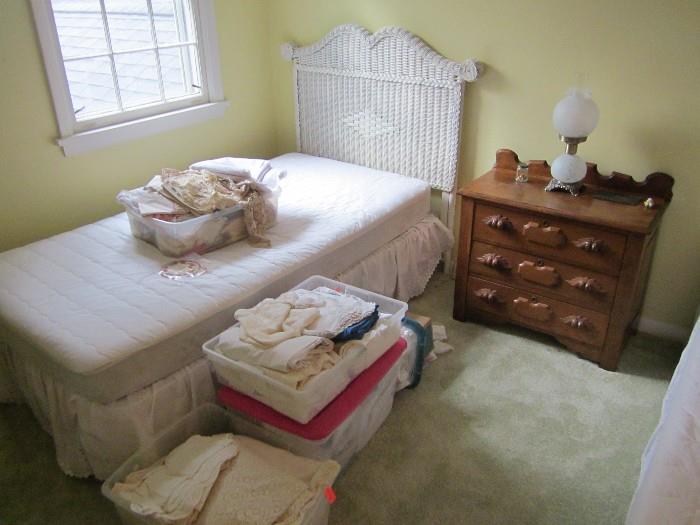 Twin wicker bed, Victorian chest & containers of linens & crochet.