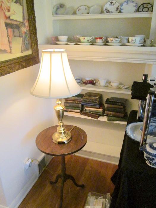 Tripod stand, lamp, books, cups & saucers.