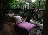 All weather wicker chaise lounge and matching round accent patio table, Cherub garden statues, French wire hanging baskets and planters, Sunbrella outdoor pillows, many plum throws