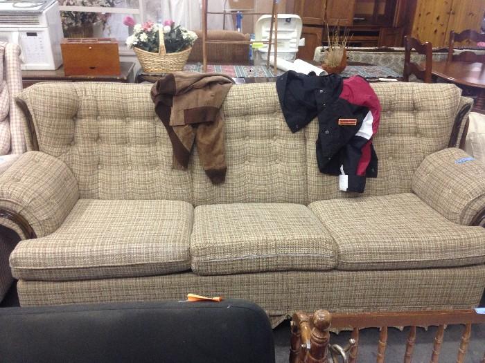 Beige Plaid Comfortable Couch with Jackets on top 