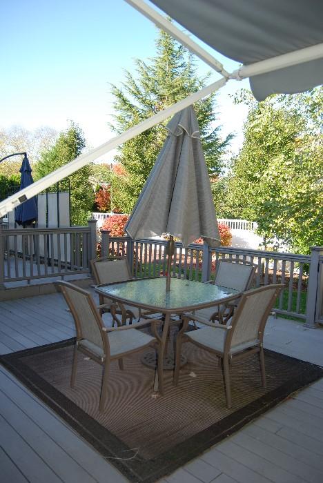 Outdoor table with 4 chairs, umbrella and base.