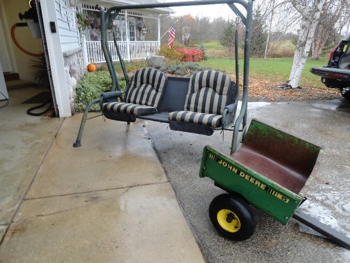 Another older porch swing with cushions.  Also shown is a small pull behind John Deere trailer.