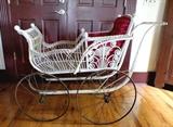 Large Victorian Carriage doll stroller in painted white washed wicker with bright red velvet padded seat and back, wire spoke wheels with metal rims and steel springs. Wheels are missing the hard rubber common for age and the stroller will need cleaned. Size: 39"H x 54"L x 19 1/2"W. Condition: Good for age.