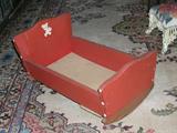 Vintage doll cradle covered in red leatherette.