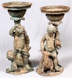 Lot#6, BRONZE FIGURAL GARDEN URNS, TWO, H 40", DIA 18"Decorated in a green patina, includes one featuring two putto figures, the other a putto riding a goat, each surmounted by round form urns, measuring H. 39 1/2" x 18 1/4" and H.. 42 1/2" x 18 1/2".