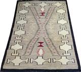 Lot#1331, NAVAJO HAND WOVEN RUG, C. 1920, 5' 11" X.Grey ground with a black border, decorated with cream and red accents. Measuring L. 5 ft. 11 x 4 ft. 5. Circa 1920.