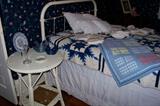 Nice painted antique iron bed - antique wicker side table with old quilts on the bed.