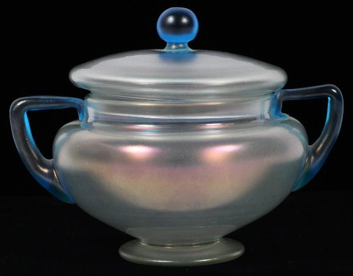 Lot#1014, STEUBEN VERRE DE SOIE GLASS SUGAR BOWL, C. 1920, H 4 1/2"Footed form covered sugar bowl, flanked by blue handles. Measuring H. 4 1/2", circa 1920.