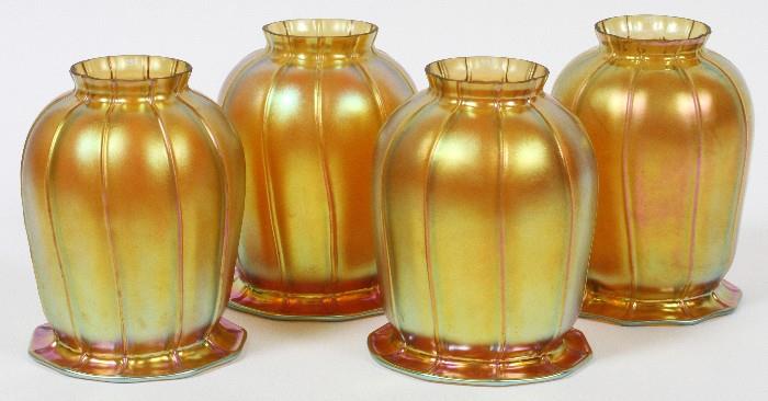 Lot#1026, STEUBEN GOLD AURENE GLASS SHADES, EARLY 20TH C., FOUR, H 5 1/4"Including four bell form gold aurene glass shades, measuring H. 5 1/4". Fitted to a fixture, measuring L. 20". Circa early 20th Century.