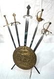 Lot 31  -  Decorative swords on shield stand base. 5 medieval style swords on a circular shield base with iron supports.-- Dimensions:  H: 44 inches: W: 35 inches: D: 19 1/4 inches --- 