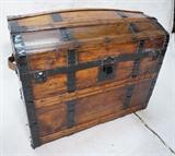 Lot 62  -  Large antique wooden chest. Bowed top, black metal straps, Leather handles. Fitted, upholstered interior. Separate compartment inside lid.-- Dimensions:  H: 27 inches: W: 32 1/2 inches: D: 20  1/2 inches --- 