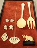Lot 275  -  7 piece carved ivory lot. 2 carved pendants, 2 pair carved earrings, set of serving fork and spoon, and carved elephant on wood base.-- Dimensions:  H: 9.5 inches ---  <br><br>US Shipping charge:</b>  $20