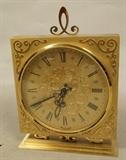 Lot 286  -  German Made Desk Clock.  Gold Tone Metal Clock.  Fancy applied decoration.  Battery op.-- Dimensions:  H: 8 inches: W: 6 inches: D: 2.25 inches ---  <br><br>US Shipping charge:</b>  $20