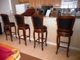 4 MAHOGANY SWIVEL BAR STOOLS IN BLACK LEATHER W/ NAILHEAD DETAIL. MATCHES COUNTER STOOLS IN KITCHEN.