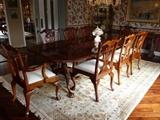 CHIPPENDALE-STYLE CARVED MAHOGANY TRIPLE PEDESTAL DINING TABLE WITH ADDITIONAL LEAVES, 2 ARMCHAIRS, AND 10 ARMLESS CHAIRS.