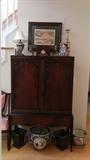 Vintage mahogany 2-door cabinet with assorted brass dust-catchers, obligatory seasonal light-up house, realistic unicorns (but no rainbows) vintage metal clock/bank, pair of metal planters.