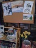 Original art tacked on the board.  Bookcase below with porcelain, china. 