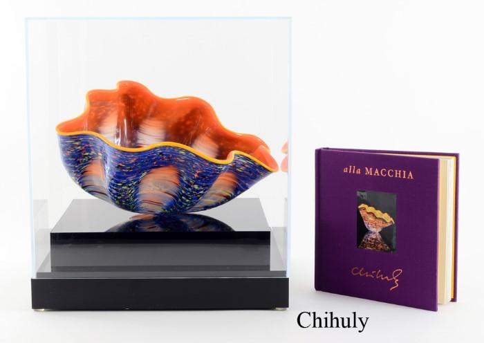 Lot 1002:  CHIHULY, Dale, (American, 1941-): Blown glass ''alla MACCHIA'' bowl, vibrant orange interior, mottled blue exterior, signed on base. In pristine condition, sold with original book with photograph of the piece and plexiglass case. Bowl measures approx. 5 3/4'' x 10 3/4'' x 9'', case measures 12'' x 10 1/2'' x 10 1/2''. Est. $3000/5000**