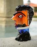 Lot 1167:  MURANO ART GLASS HEAD SCULPTURE AFTER PICASSO: Polychrome glass sculpture in the form of a stylized Piccasoesque bust, marked on base ''Italy Trip, 2008'' and illegible signature P. Bochiali?. Sold with Vetreria Ducale Glass Factory Certificate of Authenticity. Measures 9 1/4'' h. x 6'' x 3''.
CONDITION: Firing flaw to back.
