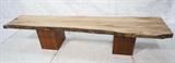 Lot 366:  8'4" Dried Sycamore 2" Slab Free Form edge Bench. Natural Edges. Slab rests on two wood cubes with double cut bands. : Dimensions:  H: 18.5 inches: D: 21 inches: L: 99.75 inches --- 