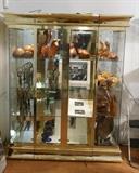 Lot 402:  MASTERCRAFT style 3 Part Brass Display Cabinet Shelf. Mirror Back & Bottom. Glass Shelves. Four Doors. Lights up. Ogee Top & Base Trim. : Dimensions:  H: 83 inches: W: 69.25 inches: D: 22.25 inches --- 