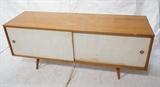 Lot 464:  Low PAUL McCOBB Sliding Door Cabinet. Maple Cabinet with White fabric sliding doors. Slanted peg legs. : Dimensions:  H: 25.5 inches: W: 60 inches: D: 18.25 inches --- 