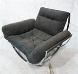 Lot 738:  Milo Baughman style Chromed Steel Wide Lounge Chair. Four opposing bowed legs. Black Pleather Cushion Seat. Not marked: Dimensions:  H: 29.5 inches: W: 42 inches: D: 40 inches --- 