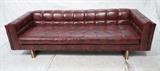 Lot 793:  Modernist Chesterfield style Couch. Wine Colored Vinyl Sofa. Wood & Chrome Base. : Dimensions:  H: 26 inches: W: 90 inches: D: 34.25 inches --- 