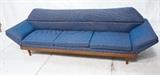 Lot 845:  Adrian Pearsall style Blue Sofa. Wide walnut skirt on peg legs. Slanted arms. : Dimensions:  H: 31 inches: W: 104 inches: D: 32 inches --- 