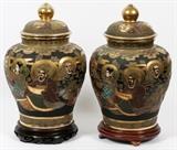 Lot#169, JAPANESE SATSUMA, EARTHENWARE COVERED URNS, 20TH C., PAIR, H 17"Baluster form urns with covers, decorated in continuous scene of figures, all on a black ground, with fired gold accents. Measuring H. 17", raised on separate wood bases. Circa 1930-1940.