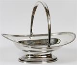 Lot#1008, TIFFANY & CO. STERLING CAKE BASKET, EARLY-MID 20TH C., H 5", L 15"Sterling silver footed cake basket, fitted with a single handle, by Tiffany & Company, a reproduction of one done by William Stevenson, London, 1801.  Stamped markings underneath indicate directorship of John C. Moore II [1907-1947], pattern number circa 1913.  Measuring H.5" x 15", with a total approximate weight of 39.31 tr.oz.