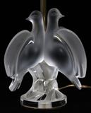 Lot#1112, LALIQUE 'ARIANE' FROSTED GLASS BOUDOIR LAMP, H 18 3/4"The frosted glass base is in the form of two doves, H.8 1/2" x 6 3/4", and is surmounted by an ivory silk shade, H.18 3/4" overall; signed "Lalique France 19" at the base.  Number 11473.