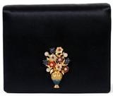 Lot#1171, JUDITH LEIBER NAVY SATIN EVENING BAG WITH JEWELED CLASP, W 6 1/4"A navy blue satin exterior with magnetic flap centered by a semi precious stone and enamel flower urn, opening to a snap pocket and matching coin purse.  Stamped: Judith Leiber, New York. Measures W.6 1/4" x 2 3/4" x 5" (24" to the detachable satin shoulder strap).